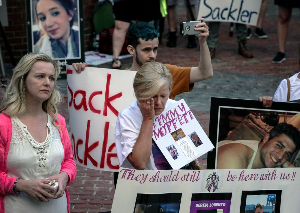 FILE - This Friday Aug. 2, 2019 file photo shows protesters who have lost love ones to the opioid crisis, outside a courthouse in Boston, Mass., where a judge heard arguments in a lawsuit against Purdue Pharma. A lawyer for the company, which is facing lawsuits over its marketing of the powerful painkiller OxyContin in driving the opioid epidemic, says states would get more money from settling rather than continuing their lawsuits against the Purdue Pharma and the Sackler family who own it. (AP Photo/Charles Krupa, File)