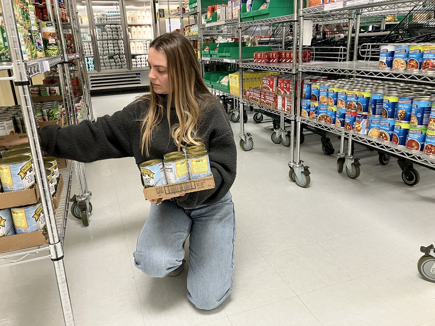 Mia Ceglie stacks canned goods at the MLK Center's temporary food pantry.