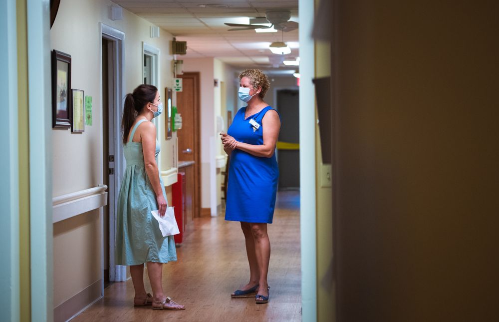 Anna Zambrano speaks with Casey Knowlton, the admissions coordinator in a hallway of the Eastgate Nursing and Rehabilitation Center.