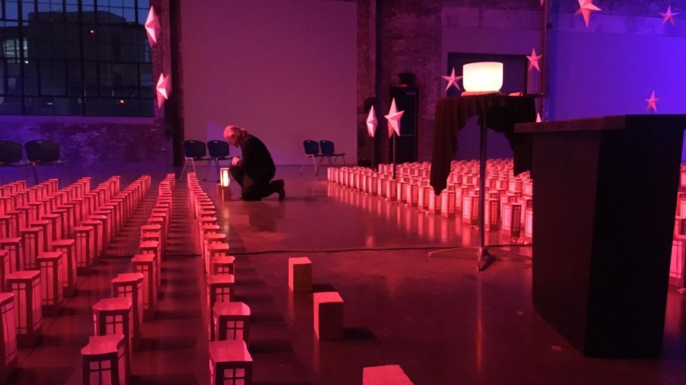 Barnaby Evans kneels to pick up one of the hundreds of luminaria representing the Rhode Islanders who have died from COVID-19