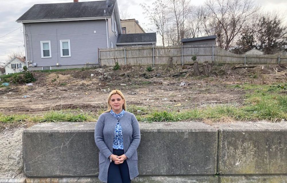 Central Falls Mayor Maria Rivera stands in a vacant lot on Lonsdale Avenue targeted for affordable housing. A lack of aid to acquire the site has stymied progress, although that could change next month.