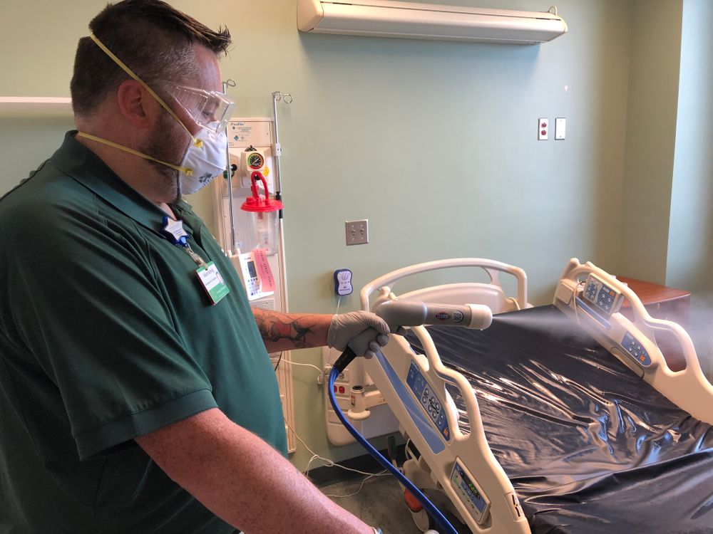 A Newport Hospital employee sanitizes a patient room with a Clorox electrostatic sprayer.