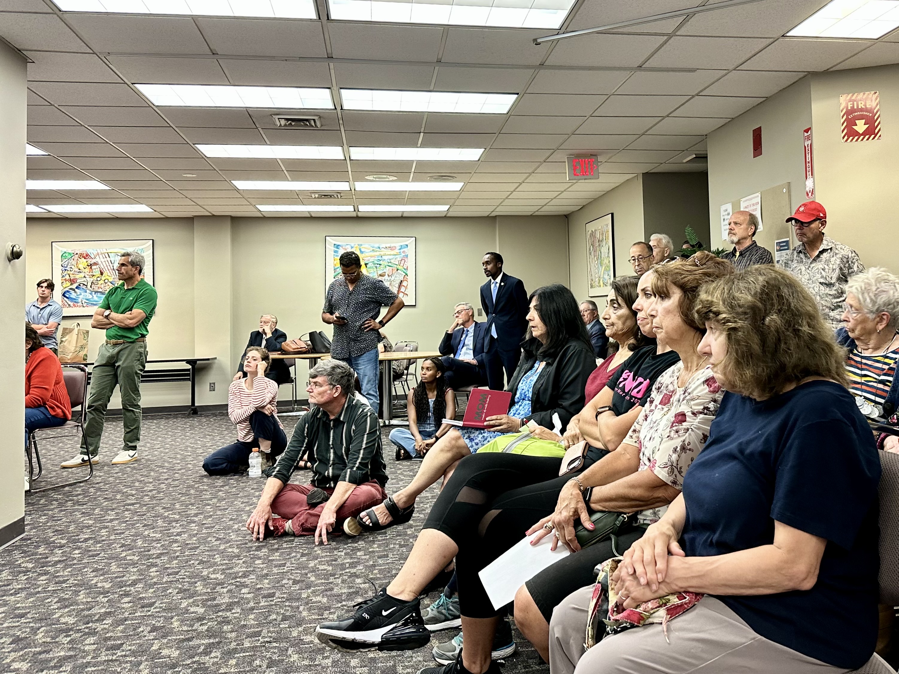 So many people showed up to the meeting that some had to sit on the floor or stand, like Fox Point city council representative John Goncalves. 