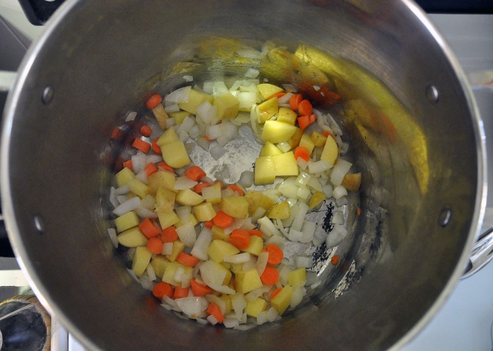 Vegetables cook inside a large pot.