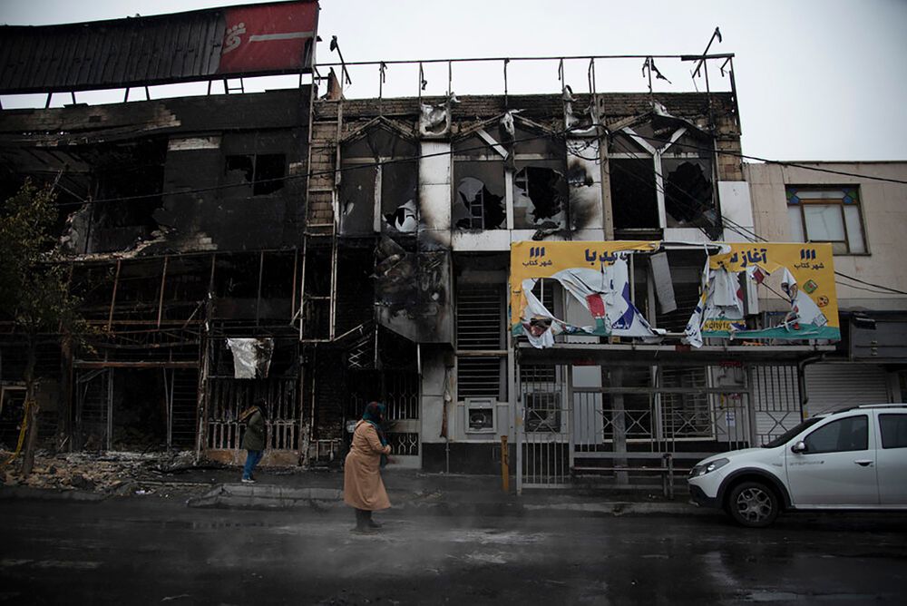 In this photo taken Monday, Nov. 18, 2019, and released by Iranian Students' News Agency, ISNA, people walk past buildings which burned during protests that followed the authorities' decision to raise gasoline prices, in the city of Karaj, west of the capital Tehran, Iran. An article published Tuesday in the Keyhan hard-line newspaper in Iran is suggesting that those who led violent protests will be executed by hanging as the unrest continues. (Masoume Aliakbar/ISNA via AP) In this photo taken Monday, Nov. 18, 2019, and released by Iranian Students' News Agency, ISNA, people walk past buildings which burned during protests that followed the authorities' decision to raise gasoline prices, in the city of Karaj, west of the capital Tehran, Iran. An article published Tuesday in the Keyhan hard-line newspaper in Iran is suggesting that those who led violent protests will be executed by hanging as the unrest continues. (Masoume Aliakbar/ISNA via AP)