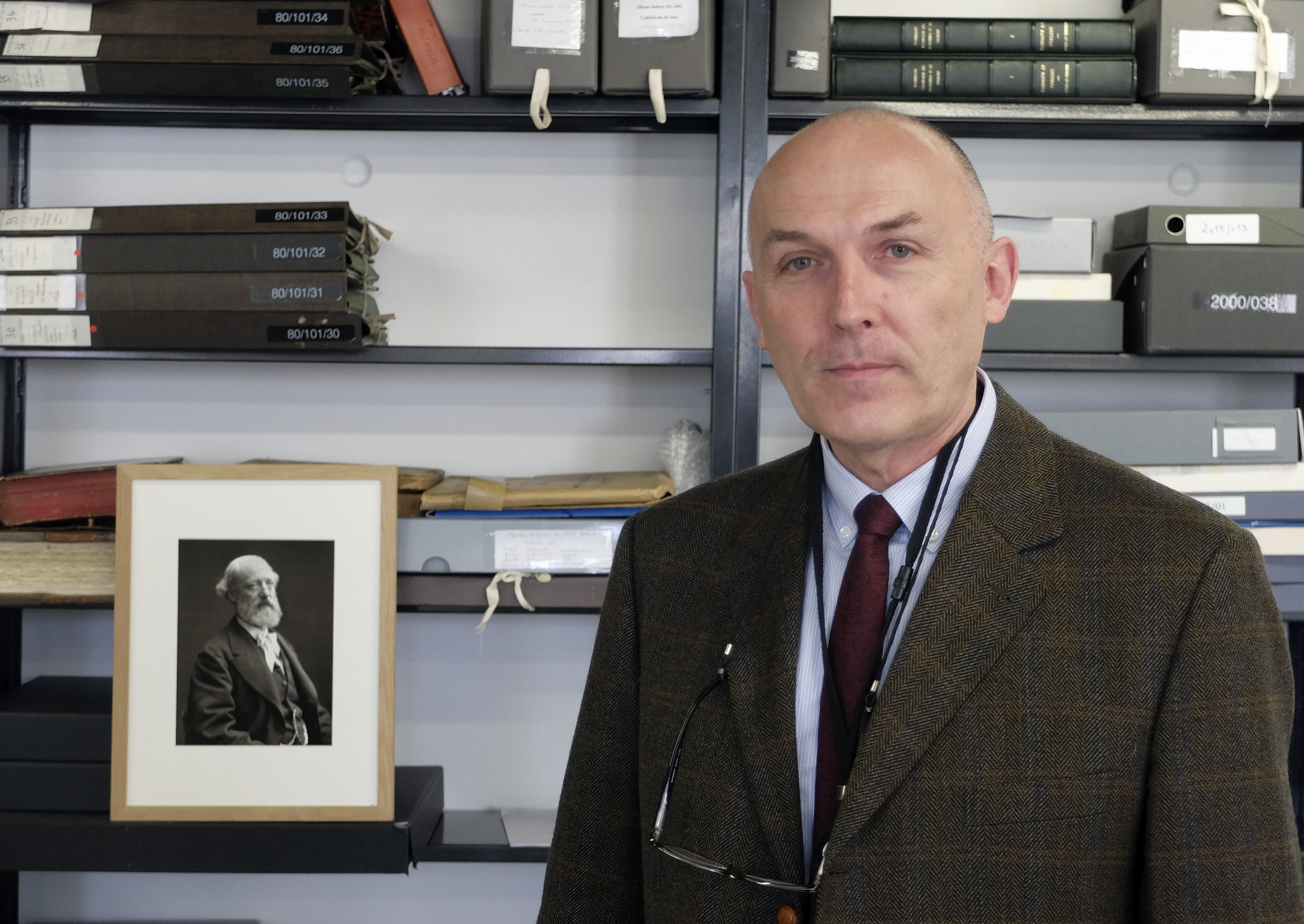 Jean-Charles Forgeret poses next to photograph of Eugene Emmanuel Viollet-le-Duc, the renowned architect who designed the spire that was added to the medieval cathedral in the 19th century, in Charenton le Pont, outside Paris, Thursday, April 18, 2019. The reconstruction of Paris' Notre Dame Cathedral will rely on part on extensive plans drawn up in the 19th century for its last big renovation. Forgeret noted that the last restoration took 20 years, and cast doubt on the French president's 5-year deadline on fixing Notre Dame this time. (AP Photo/Nicolas Garriga) Jean-Charles Forgeret poses next to photograph of Eugene Emmanuel Viollet-le-Duc, the renowned architect who designed the spire that was added to the medieval cathedral in the 19th century, in Charenton le Pont, outside Paris, Thursday, April 18, 2019. The reconstruction of Paris' Notre Dame Cathedral will rely on part on extensive plans drawn up in the 19th century for its last big renovation. Forgeret noted that the last restoration took 20 years, and cast doubt on the French president's 5-year deadline on fixing Notre Dame this time. (AP Photo/Nicolas Garriga)