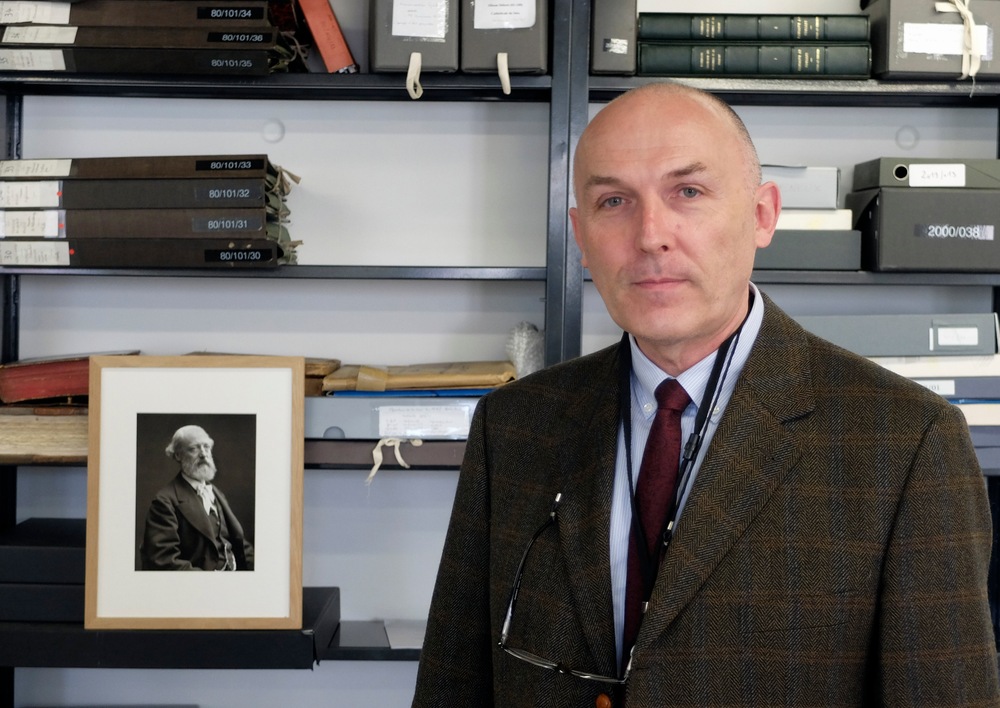 Jean-Charles Forgeret poses next to photograph of Eugene Emmanuel Viollet-le-Duc, the renowned architect who designed the spire that was added to the medieval cathedral in the 19th century, in Charenton le Pont, outside Paris, Thursday, April 18, 2019. The reconstruction of Paris' Notre Dame Cathedral will rely on part on extensive plans drawn up in the 19th century for its last big renovation. Forgeret noted that the last restoration took 20 years, and cast doubt on the French president's 5-year deadline on fixing Notre Dame this time. (AP Photo/Nicolas Garriga) Jean-Charles Forgeret poses next to photograph of Eugene Emmanuel Viollet-le-Duc, the renowned architect who designed the spire that was added to the medieval cathedral in the 19th century, in Charenton le Pont, outside Paris, Thursday, April 18, 2019. The reconstruction of Paris' Notre Dame Cathedral will rely on part on extensive plans drawn up in the 19th century for its last big renovation. Forgeret noted that the last restoration took 20 years, and cast doubt on the French president's 5-year deadline on fixing Notre Dame this time. (AP Photo/Nicolas Garriga)