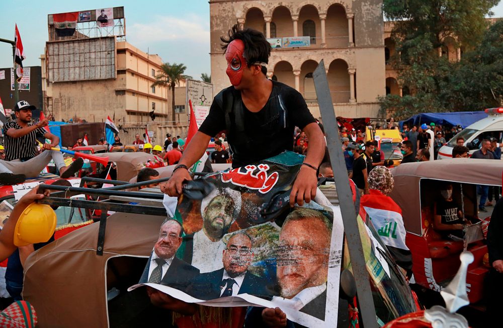 A masked protester hits a poster showing Iraqi politicians and militia leaders with a shoe, during ongoing anti-government protests in Baghdad, Iraq, Sunday, Nov. 3, 2019. (AP Photo) A masked protester hits a poster showing Iraqi politicians and militia leaders with a shoe, during ongoing anti-government protests in Baghdad, Iraq, Sunday, Nov. 3, 2019. (AP Photo)