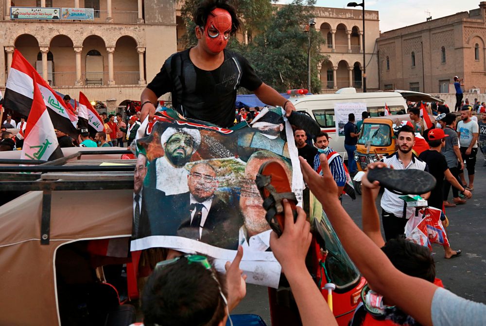 Protesters hit a poster showing Iraqi politicians and militia leaders with a shoe, during ongoing anti-government protests in Baghdad, Iraq, Sunday, Nov. 3, 2019. (AP Photo) Protesters hit a poster showing Iraqi politicians and militia leaders with a shoe, during ongoing anti-government protests in Baghdad, Iraq, Sunday, Nov. 3, 2019. (AP Photo)