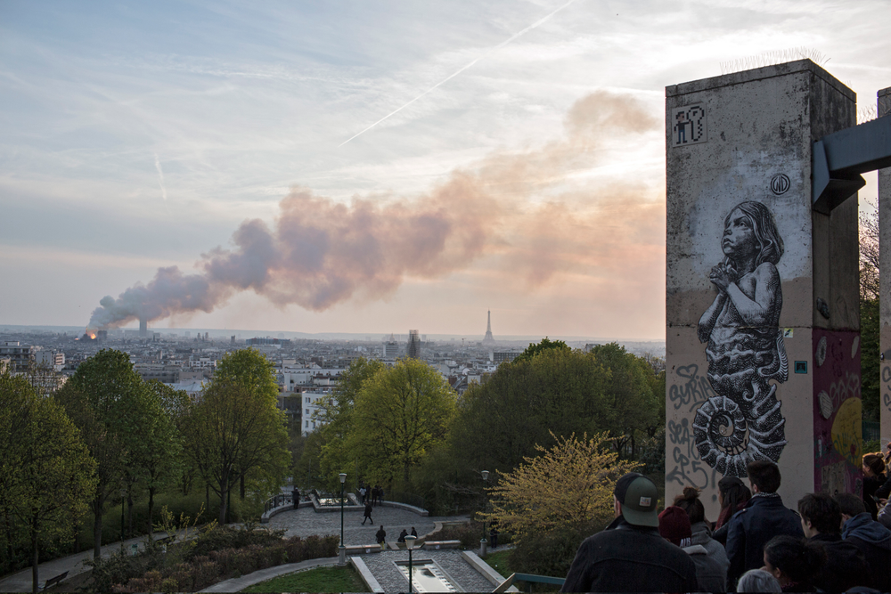 People watch Notre Dame cathedral burning in Paris, Monday, April 15, 2019. Massive plumes of yellow brown smoke is filling the air above Notre Dame Cathedral and ash is falling on tourists and others around the island that marks the center of Paris. (AP Photo/Rafael Yaghobzadeh) People watch Notre Dame cathedral burning in Paris, Monday, April 15, 2019. Massive plumes of yellow brown smoke is filling the air above Notre Dame Cathedral and ash is falling on tourists and others around the island that marks the center of Paris. (AP Photo/Rafael Yaghobzadeh)