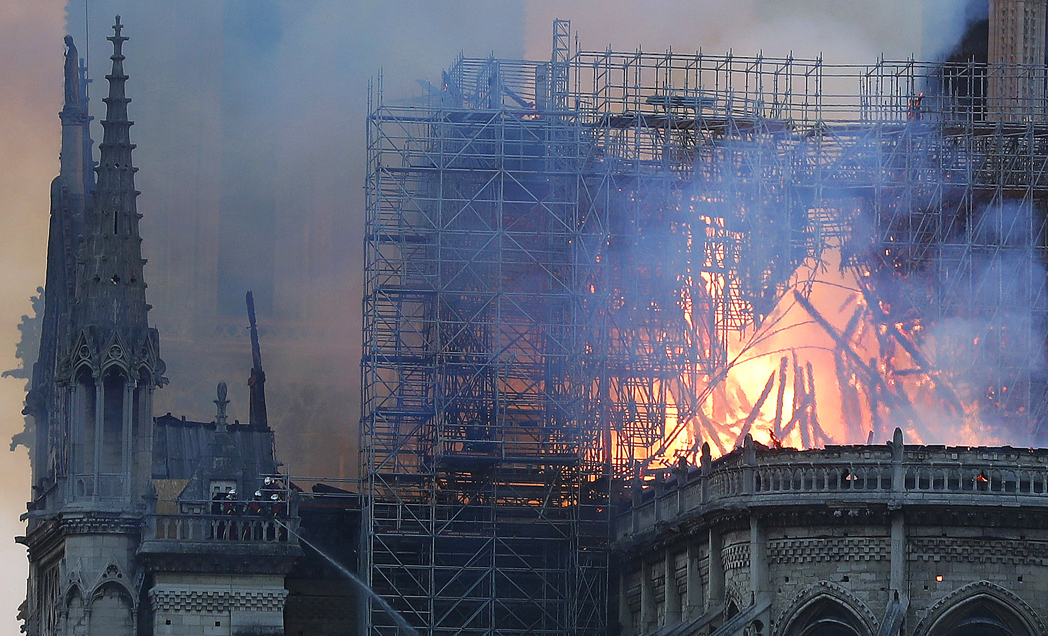 Firefighters tackle the blaze as flames and smoke rise from Notre Dame cathedral as it burns in Paris, Monday, April 15, 2019. Massive plumes of yellow brown smoke is filling the air above Notre Dame Cathedral and ash is falling on tourists and others around the island that marks the center of Paris. (AP Photo/Thibault Camus) Firefighters tackle the blaze as flames and smoke rise from Notre Dame cathedral as it burns in Paris, Monday, April 15, 2019. Massive plumes of yellow brown smoke is filling the air above Notre Dame Cathedral and ash is falling on tourists and others around the island that marks the center of Paris. (AP Photo/Thibault Camus)