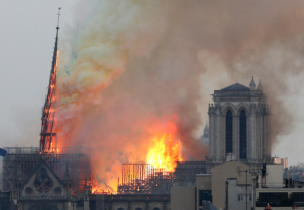 Flames rise from Notre Dame cathedral as it burns in Paris, Monday, April 15, 2019. Massive plumes of yellow brown smoke is filling the air above Notre Dame Cathedral and ash is falling on tourists and others around the island that marks the center of Paris. (AP Photo/Thibault Camus) Flames rise from Notre Dame cathedral as it burns in Paris, Monday, April 15, 2019. Massive plumes of yellow brown smoke is filling the air above Notre Dame Cathedral and ash is falling on tourists and others around the island that marks the center of Paris. (AP Photo/Thibault Camus)