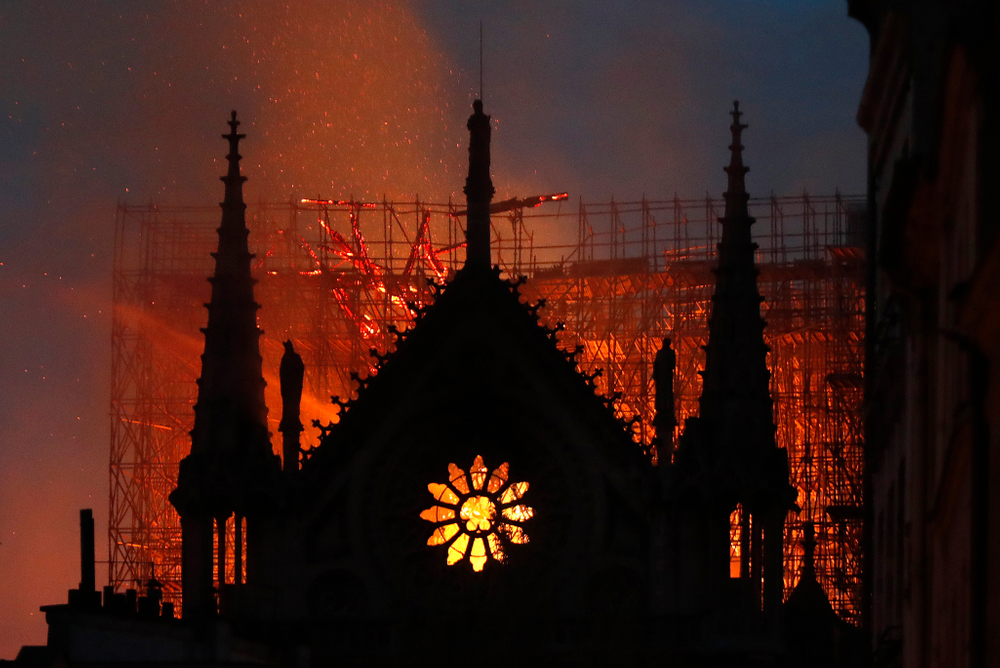 Flames and smoke rise from Notre Dame cathedral as it burns in Paris, Monday, April 15, 2019. Massive plumes of yellow brown smoke is filling the air above Notre Dame Cathedral and ash is falling on tourists and others around the island that marks the center of Paris. (AP Photo/Thibault Camus) Flames and smoke rise from Notre Dame cathedral as it burns in Paris, Monday, April 15, 2019. Massive plumes of yellow brown smoke is filling the air above Notre Dame Cathedral and ash is falling on tourists and others around the island that marks the center of Paris. (AP Photo/Thibault Camus)