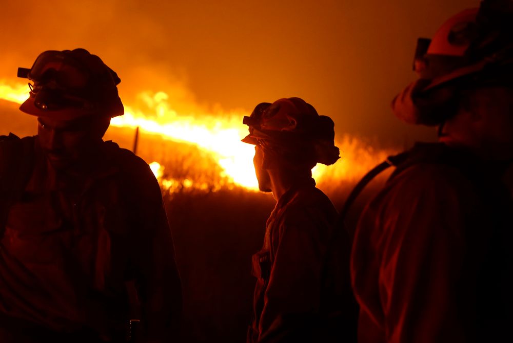 FILE - In this Sept. 12, 2015 file photo, California Department of Corrections and Rehabilitation inmates stand guard as flames from the Butte Fire approach a containment line near San Andreas, Calif. Attorneys representing 14 local governments said Tuesday, June 18, 2019 that they had reached a $1 billion settlement with California utility Pacific Gas & Electric for a series of fires dating to 2015. (AP Photo/Rich Pedroncelli, File) FILE - In this Sept. 12, 2015 file photo, California Department of Corrections and Rehabilitation inmates stand guard as flames from the Butte Fire approach a containment line near San Andreas, Calif. Attorneys representing 14 local governments said Tuesday, June 18, 2019 that they had reached a $1 billion settlement with California utility Pacific Gas & Electric for a series of fires dating to 2015. (AP Photo/Rich Pedroncelli, File)