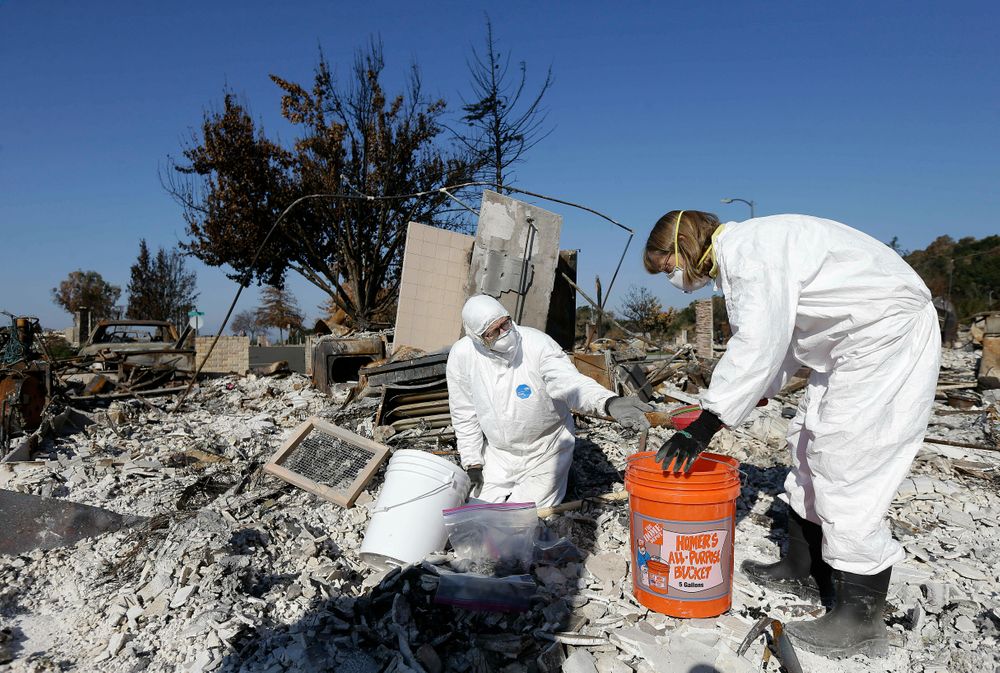 FILE - In this Tuesday, Oct. 31, 2017, file photo, David Rust, left, and his wife Shelly search through the remains of their home destroyed by wildfires in Santa Rosa, Calif. Attorneys representing 14 local governments said Tuesday, June 18, 2019, that they had reached a $1 billion settlement with California utility Pacific Gas & Electric for a series of fires dating to 2015. (AP Photo/Jeff Chiu, File) FILE - In this Tuesday, Oct. 31, 2017, file photo, David Rust, left, and his wife Shelly search through the remains of their home destroyed by wildfires in Santa Rosa, Calif. Attorneys representing 14 local governments said Tuesday, June 18, 2019, that they had reached a $1 billion settlement with California utility Pacific Gas & Electric for a series of fires dating to 2015. (AP Photo/Jeff Chiu, File)