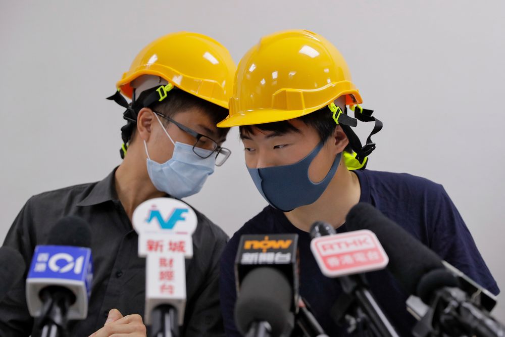 Protesters Jerry Chan, right, chats with Linus Kim during a press conference in Hong Kong, Tuesday, Aug. 6, 2019. Hong Kong protesters Tuesday condemned what they call the government's Protesters Jerry Chan, right, chats with Linus Kim during a press conference in Hong Kong, Tuesday, Aug. 6, 2019. Hong Kong protesters Tuesday condemned what they call the government's