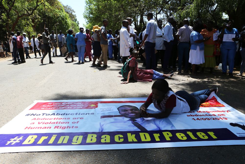 A Zimbabwean doctor lays on a banner with a portrait of fellow missing doctor, Peter Magombeyi, in Harare, Wednesday, Sept, 18, 2019. Zimbabwean doctors protesting the alleged abduction of a union leader were met by a line of baton- wielding police in the capital as fears grow about government repression. (AP Photo/Tsvangirayi Mukwazhi) A Zimbabwean doctor lays on a banner with a portrait of fellow missing doctor, Peter Magombeyi, in Harare, Wednesday, Sept, 18, 2019. Zimbabwean doctors protesting the alleged abduction of a union leader were met by a line of baton- wielding police in the capital as fears grow about government repression. (AP Photo/Tsvangirayi Mukwazhi)