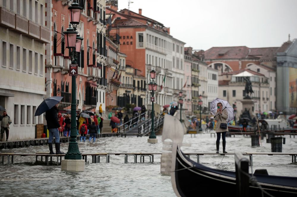 A woman standing on catwalk, right, set up on the occasion of a high tide takes pictures, in a flooded Venice, Italy, Tuesday, Nov. 12, 2019. The high tide reached a peak of 127cm (4.1ft) at 10:35am while an even higher level of 140cm(4.6ft) was predicted for later Tuesday evening. (AP Photo/Luca Bruno) A woman standing on catwalk, right, set up on the occasion of a high tide takes pictures, in a flooded Venice, Italy, Tuesday, Nov. 12, 2019. The high tide reached a peak of 127cm (4.1ft) at 10:35am while an even higher level of 140cm(4.6ft) was predicted for later Tuesday evening. (AP Photo/Luca Bruno)