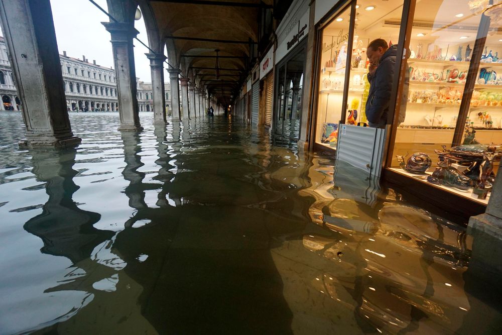 A shopkeeper looks out of his shop at a flooded St. Mark's Square on the occasion of a high tide, in Venice, Italy, Tuesday, Nov. 12, 2019. The high tide reached a peak of 127cm (4.1ft) at 10:35am while an even higher level of 140cm(4.6ft) was predicted for later Tuesday evening. (Andrea Merola/ANSA via AP) A shopkeeper looks out of his shop at a flooded St. Mark's Square on the occasion of a high tide, in Venice, Italy, Tuesday, Nov. 12, 2019. The high tide reached a peak of 127cm (4.1ft) at 10:35am while an even higher level of 140cm(4.6ft) was predicted for later Tuesday evening. (Andrea Merola/ANSA via AP)