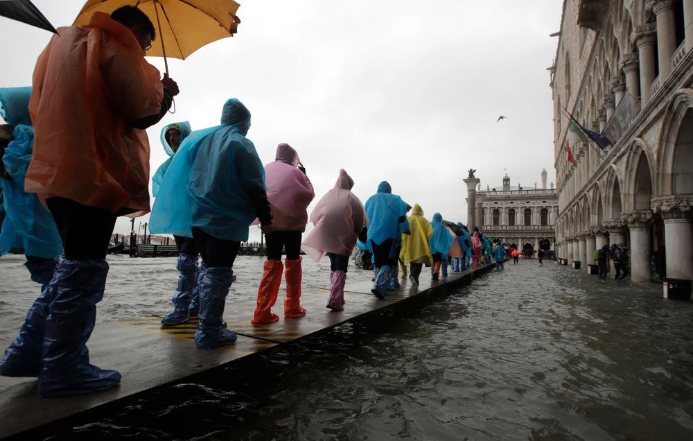 People walk on catwalk set up on the occasion of a high tide, in a flooded Venice, Italy, Tuesday, Nov. 12, 2019. The high tide reached a peak of 127cm (4.1ft) at 10:35am while an even higher level of 140cm(4.6ft) was predicted for later Tuesday evening. (AP Photo/Luca Bruno) People walk on catwalk set up on the occasion of a high tide, in a flooded Venice, Italy, Tuesday, Nov. 12, 2019. The high tide reached a peak of 127cm (4.1ft) at 10:35am while an even higher level of 140cm(4.6ft) was predicted for later Tuesday evening. (AP Photo/Luca Bruno)