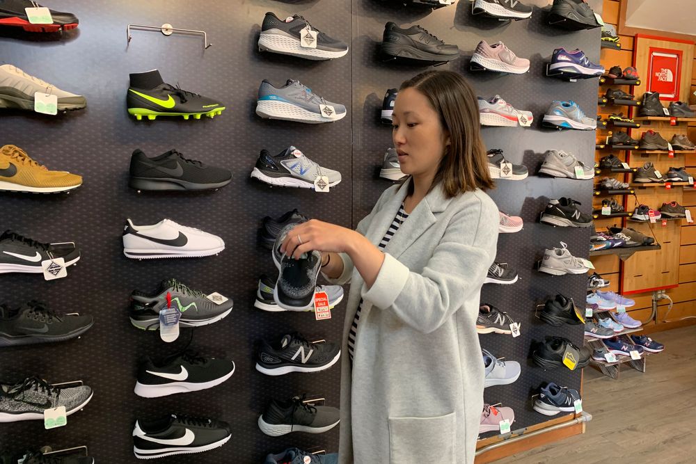 In this photo taken Wednesday, Aug. 28, 2019, Jennifer Lee, whose family owns Footprint shoe store in San Francisco, stands by a wall of athletic shoes, many of which are made in China and will be subject to new U.S. tariffs on Chinese goods starting Sept 1. (AP Photo/Terry Chea) In this photo taken Wednesday, Aug. 28, 2019, Jennifer Lee, whose family owns Footprint shoe store in San Francisco, stands by a wall of athletic shoes, many of which are made in China and will be subject to new U.S. tariffs on Chinese goods starting Sept 1. (AP Photo/Terry Chea)