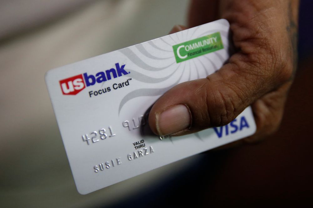 In this photo taken Wednesday, Aug. 14, 2019, Susie Garza displays the city provided debit card she receives monthly through a trial program in Stockton, Calif. Garza is participating in the Stockton Economic Empowerment Demonstration. The program, which started in February, gives $500 a month to 125 people who earn at or below the median household income of $46,033. They can spend the money with no restrictions. Stockton Mayor Michael Tubbs, who initiated the privately funded program, says it could be a solution to the city's poverty problem. (AP Photo/Rich Pedroncelli) In this photo taken Wednesday, Aug. 14, 2019, Susie Garza displays the city provided debit card she receives monthly through a trial program in Stockton, Calif. Garza is participating in the Stockton Economic Empowerment Demonstration. The program, which started in February, gives $500 a month to 125 people who earn at or below the median household income of $46,033. They can spend the money with no restrictions. Stockton Mayor Michael Tubbs, who initiated the privately funded program, says it could be a solution to the city's poverty problem. (AP Photo/Rich Pedroncelli)