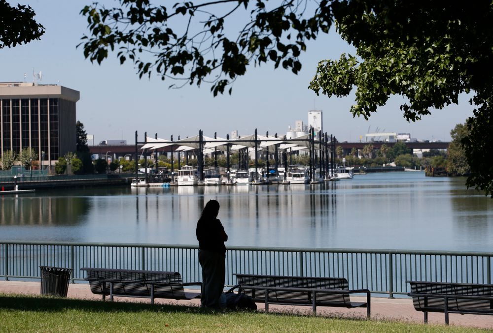 In this photo taken Wednesday, Aug. 14, 2019, a visitor takes in the view of the waterfront in Stockton, Calif. The area as been targeted for redevelopment as Stockton continues to revere from the Great Recession when it known as the foreclosure capital of the country and for one of the nation's largest municipal bankruptcies. Now, it's led by Mayor Michael Tubbs who has initiated a program to give 125 people who earn at or below the median household income of $46,033 receive a $500 debit card each month to spend any what they want. Tubbs says the program, which is privately funded, could be a solution to the city's poverty problem. (AP Photo/Rich Pedroncelli) In this photo taken Wednesday, Aug. 14, 2019, a visitor takes in the view of the waterfront in Stockton, Calif. The area as been targeted for redevelopment as Stockton continues to revere from the Great Recession when it known as the foreclosure capital of the country and for one of the nation's largest municipal bankruptcies. Now, it's led by Mayor Michael Tubbs who has initiated a program to give 125 people who earn at or below the median household income of $46,033 receive a $500 debit card each month to spend any what they want. Tubbs says the program, which is privately funded, could be a solution to the city's poverty problem. (AP Photo/Rich Pedroncelli)