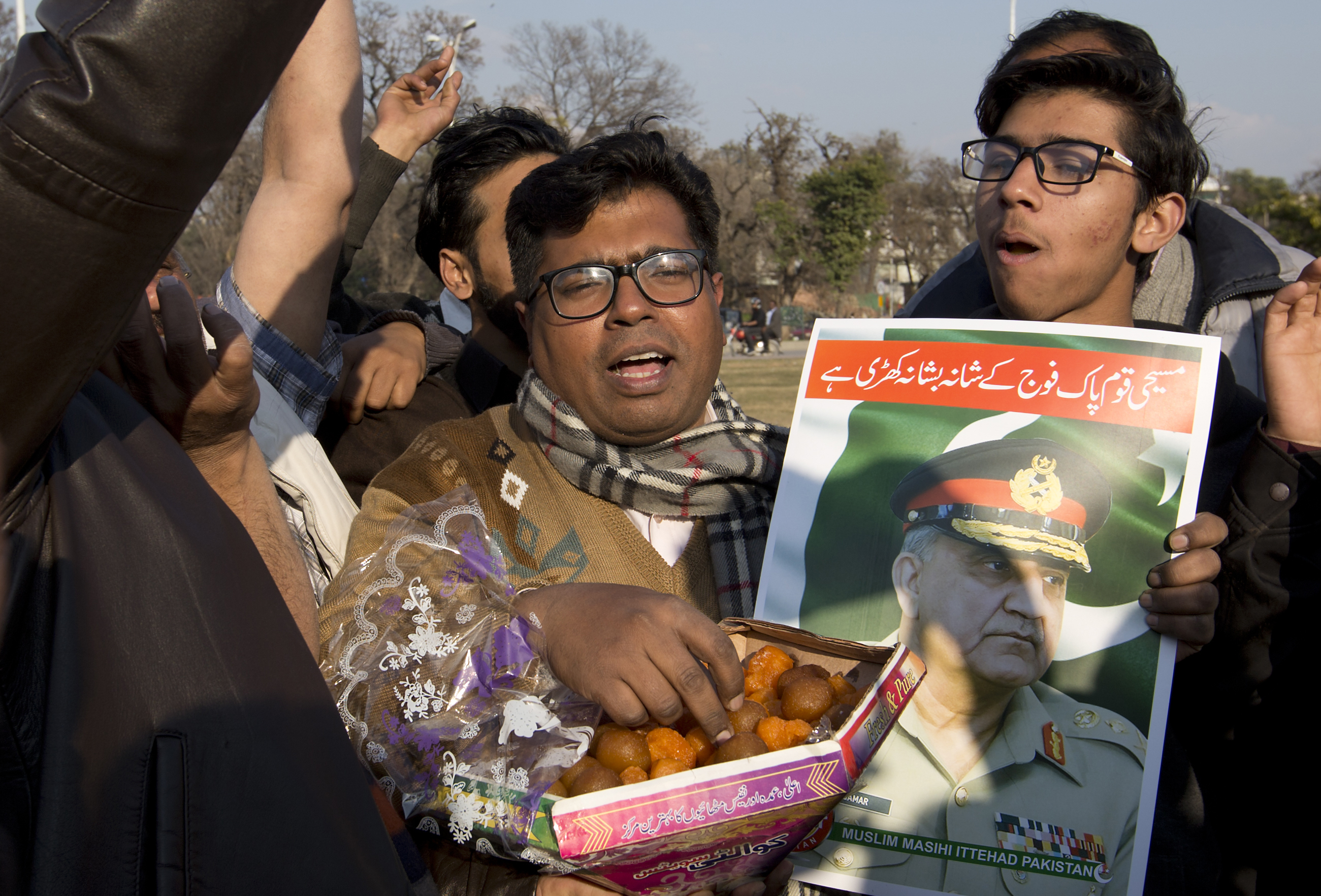 People holding a poster of Pakistani army chief exchange sweets to celebrate the shooting down Indian planes by Pakistani forces, outside in Islamabad, Pakistan, Wednesday, Feb. 27, 2019. Pakistan's military said Wednesday it shot down two Indian warplanes in the disputed region of Kashmir and captured two pilots, raising tensions between the nuclear-armed rivals to a level unseen in 20 years. (AP Photo/B.K. Bangash) People holding a poster of Pakistani army chief exchange sweets to celebrate the shooting down Indian planes by Pakistani forces, outside in Islamabad, Pakistan, Wednesday, Feb. 27, 2019. Pakistan's military said Wednesday it shot down two Indian warplanes in the disputed region of Kashmir and captured two pilots, raising tensions between the nuclear-armed rivals to a level unseen in 20 years. (AP Photo/B.K. Bangash)