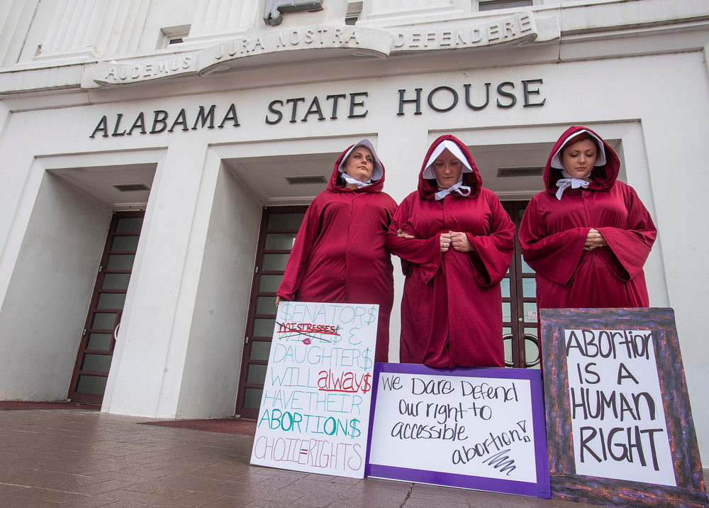 FILE - In this April 17, 2019, file photo, Bianca Cameron-Schwiesow, from left, Kari Crowe and Margeaux Hartline, dressed as handmaids, protest against a bill banning nearly all abortions at the Alabama State House in Montgomery, Ala. As abortion opponents cheer the passage of fetal heartbeat laws and other restrictions on the procedure, abortion-rights groups have been waging a quieter battle in courthouses around the country to overturn limits on providers. (Mickey Welsh/The Montgomery Advertiser via AP, File) FILE - In this April 17, 2019, file photo, Bianca Cameron-Schwiesow, from left, Kari Crowe and Margeaux Hartline, dressed as handmaids, protest against a bill banning nearly all abortions at the Alabama State House in Montgomery, Ala. As abortion opponents cheer the passage of fetal heartbeat laws and other restrictions on the procedure, abortion-rights groups have been waging a quieter battle in courthouses around the country to overturn limits on providers. (Mickey Welsh/The Montgomery Advertiser via AP, File)