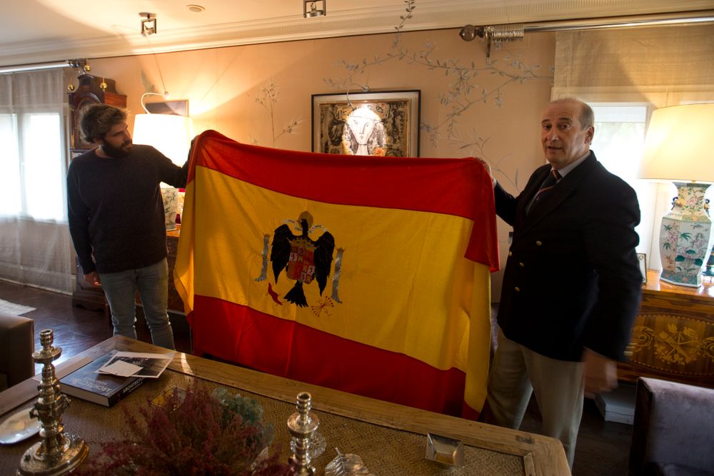 Spanish dictator General Francisco Franco's grandson, Francisco Franco Martinez-Bordiu, right, and his son Alvaro hold up a pre-constitutional Spanish flag they want draped over the coffin General Franco during his reburial Thursday after an interview with The Associated Press in Madrid, Spain, Wednesday, Oct. 23, 2019. Weather permitting, the Spanish dictator's preserved body will be flown Thursday by helicopter to the Franco family's private chapel in the Mingorrubio cemetery. It's a discrete site compared to the Valley of the Fallen, a vainglorious mausoleum and basilica that Franco built and where he was buried in 1975. The complex, which is topped by a 152-meter (500-foot) granite cross that can be seen for miles, still remains a National Heritage site. (AP Photo/Paul White) Spanish dictator General Francisco Franco's grandson, Francisco Franco Martinez-Bordiu, right, and his son Alvaro hold up a pre-constitutional Spanish flag they want draped over the coffin General Franco during his reburial Thursday after an interview with The Associated Press in Madrid, Spain, Wednesday, Oct. 23, 2019. Weather permitting, the Spanish dictator's preserved body will be flown Thursday by helicopter to the Franco family's private chapel in the Mingorrubio cemetery. It's a discrete site compared to the Valley of the Fallen, a vainglorious mausoleum and basilica that Franco built and where he was buried in 1975. The complex, which is topped by a 152-meter (500-foot) granite cross that can be seen for miles, still remains a National Heritage site. (AP Photo/Paul White)