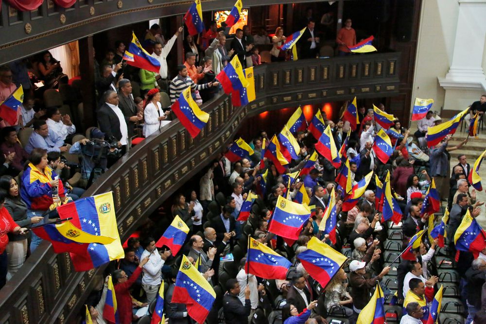 Members of the National Constituent Assembly wave Venezuelan flags during a session by the legislative body that is stacked with government allies that rivals the opposition-controlled National Assembly in Caracas, Venezuela, Monday, Aug. 12, 2019. Legislators loyal to Venezuelan President Nicolás Maduro on Monday stripped immunity from four opposition lawmakers accused of treason amid a struggle for control of the crisis-stricken nation, bringing to 18 the number of opposition politicians Maduro's government has threatened with criminal prosecution this year. (AP Photo/Leonardo Fernandez) Members of the National Constituent Assembly wave Venezuelan flags during a session by the legislative body that is stacked with government allies that rivals the opposition-controlled National Assembly in Caracas, Venezuela, Monday, Aug. 12, 2019. Legislators loyal to Venezuelan President Nicolás Maduro on Monday stripped immunity from four opposition lawmakers accused of treason amid a struggle for control of the crisis-stricken nation, bringing to 18 the number of opposition politicians Maduro's government has threatened with criminal prosecution this year. (AP Photo/Leonardo Fernandez)
