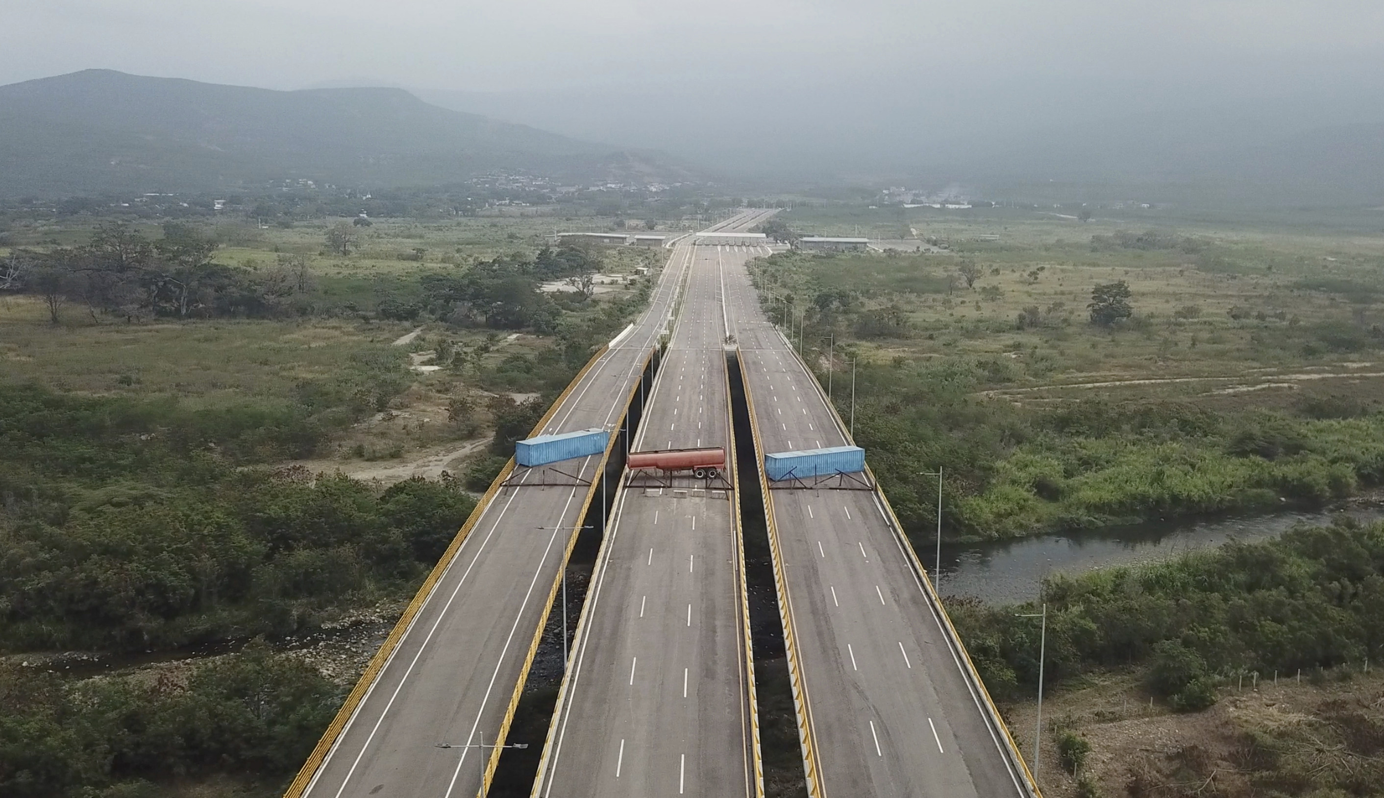 This image taken from video, shows a fuel tanker, cargo trailers and makeshift fencing, blocking the Tienditas International Bridge in an attempt to stop humanitarian aid entering from Colombia, as seen from the outskirts of Cucuta, on Colombia's border with Venezuela, Wednesday, Feb. 6, 2019. Immigration authorities say the Venezuelan National Guard built the roadblock a day earlier. (AP Photo) This image taken from video, shows a fuel tanker, cargo trailers and makeshift fencing, blocking the Tienditas International Bridge in an attempt to stop humanitarian aid entering from Colombia, as seen from the outskirts of Cucuta, on Colombia's border with Venezuela, Wednesday, Feb. 6, 2019. Immigration authorities say the Venezuelan National Guard built the roadblock a day earlier. (AP Photo)