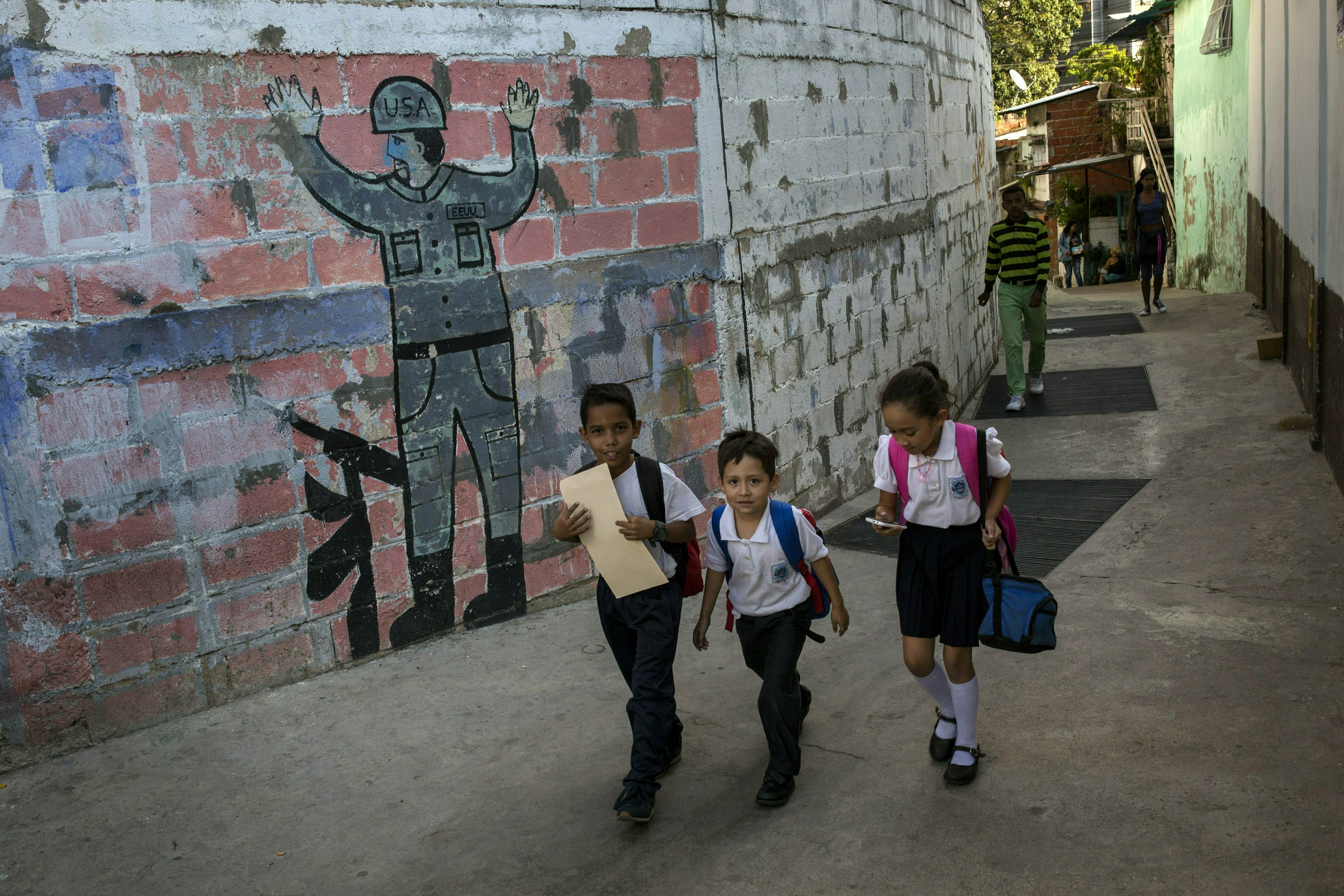 In this Feb. 1, 2019 photo, children walk past a mural that depicts the surrender of a U.S. soldier, in Caracas, Venezuela. Caritas, a charity run by the Roman Catholic church, estimates that child malnutrition more than doubled last year in Venezuela due to widespread food shortages and 7-digit hyperinflation, while 48 percent of pregnant women in low-income neighborhoods are also underfed. (AP Photo/Rodrigo Abd) In this Feb. 1, 2019 photo, children walk past a mural that depicts the surrender of a U.S. soldier, in Caracas, Venezuela. Caritas, a charity run by the Roman Catholic church, estimates that child malnutrition more than doubled last year in Venezuela due to widespread food shortages and 7-digit hyperinflation, while 48 percent of pregnant women in low-income neighborhoods are also underfed. (AP Photo/Rodrigo Abd)