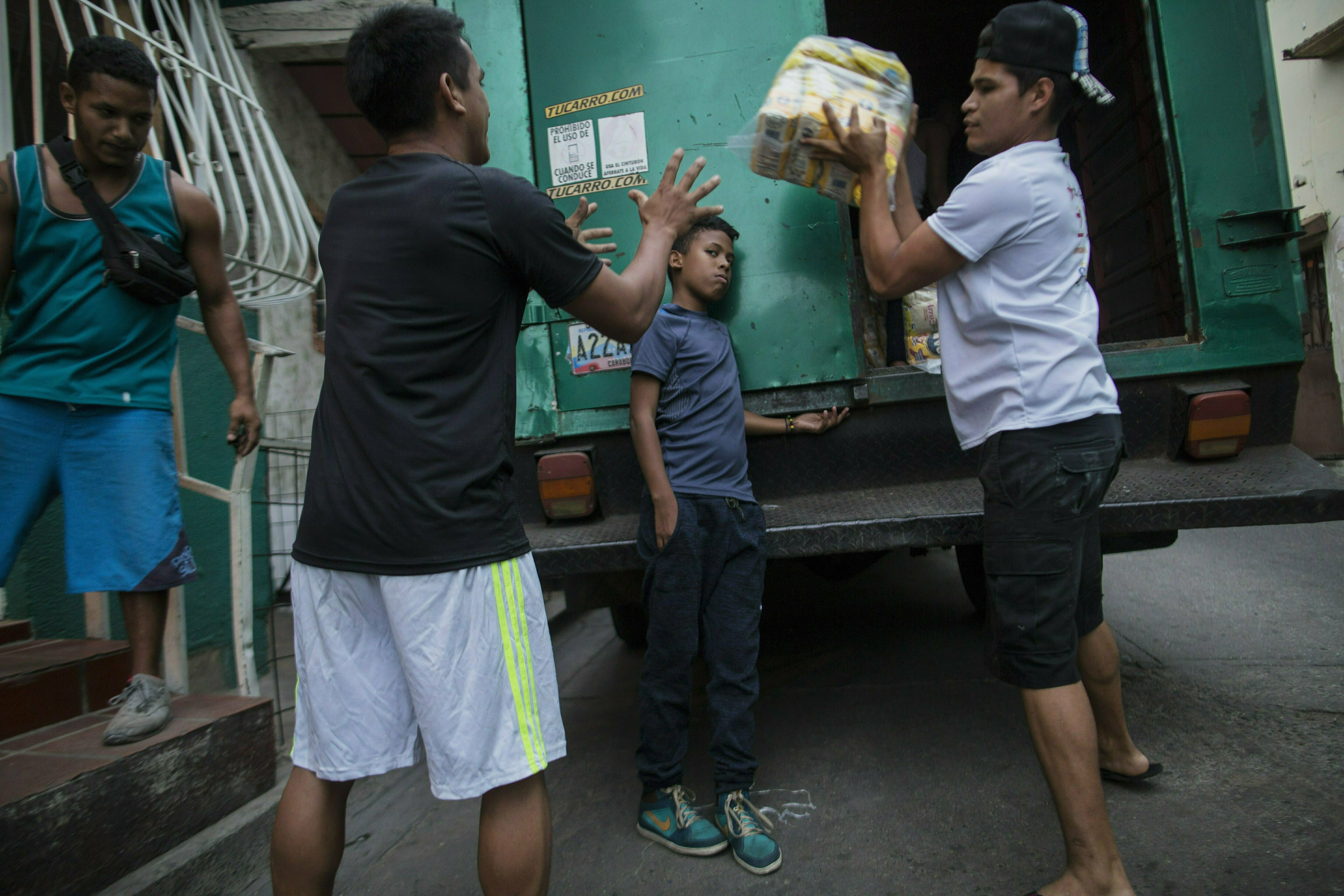 In this Jan. 31, 2019 photo, neighbors unload subsidized food distributed under a government program called In this Jan. 31, 2019 photo, neighbors unload subsidized food distributed under a government program called