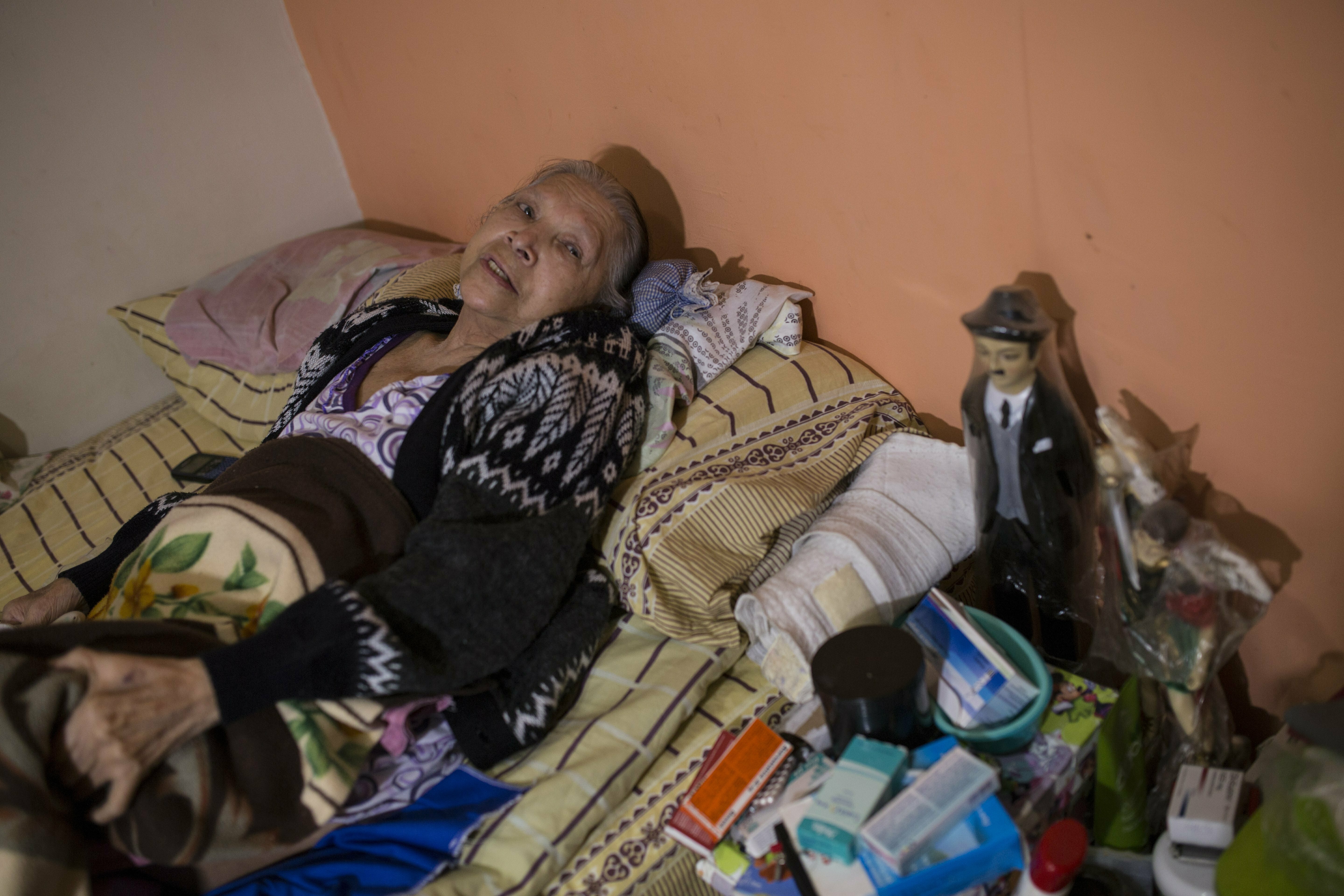 In this Feb. 4, 2019 photo, diabetes patient Aminta Villamizar lies on her bed next to a statue of Dr. Jose Greogrio Hernandez, a 19th century Venezuelan doctor who treated the poor and is revered throughout the country as a saint, in Caracas, Venezuela. “I was a person who worked my entire life, but this sickness destroyed me,” she said, complaining of joint pain and blurry vision. “If we don’t receive help, we’ll have to resign ourselves to God’s will.” (AP Photo/Rodrigo Abd) In this Feb. 4, 2019 photo, diabetes patient Aminta Villamizar lies on her bed next to a statue of Dr. Jose Greogrio Hernandez, a 19th century Venezuelan doctor who treated the poor and is revered throughout the country as a saint, in Caracas, Venezuela. “I was a person who worked my entire life, but this sickness destroyed me,” she said, complaining of joint pain and blurry vision. “If we don’t receive help, we’ll have to resign ourselves to God’s will.” (AP Photo/Rodrigo Abd)