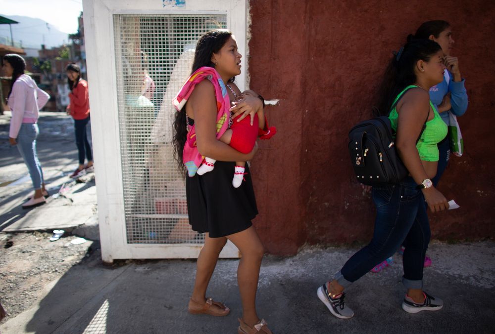 In this photo taken July 25, 2019, 15-year-old Nicol Ramirez carries her baby girl into a clinic where she hopes to get a hormonal implant to prevent future pregnancies in the Caucaguita neighborhood on the outskirts of Caracas, Venezuela. Ramírez and her sister were among the lucky few to get the last of the implants after their mom paid for a pregnancy test and they were able to prove they were not pregnant. (AP Photo/Ariana Cubillos) In this photo taken July 25, 2019, 15-year-old Nicol Ramirez carries her baby girl into a clinic where she hopes to get a hormonal implant to prevent future pregnancies in the Caucaguita neighborhood on the outskirts of Caracas, Venezuela. Ramírez and her sister were among the lucky few to get the last of the implants after their mom paid for a pregnancy test and they were able to prove they were not pregnant. (AP Photo/Ariana Cubillos)
