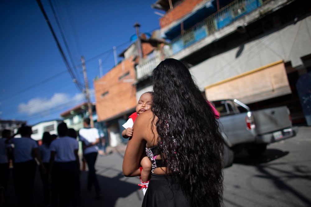 In this photo taken July 25, 2019, 15-year-old Nicol Ramirez carries her baby girl to a lab where she will pay to get a pregnancy test, a prerequisite for a hormonal implant to prevent future pregnancies, of which there is a very limited number, in the Caucaguita neighborhood on the outskirts of Caracas, Venezuela. With condoms and birth control pills either impossible to find or too expensive, Ramírez found out she was pregnant at 14 with her boyfriend, who responded coldly to her pregnancy and hasn't heard from him since. (AP Photo/Ariana Cubillos) In this photo taken July 25, 2019, 15-year-old Nicol Ramirez carries her baby girl to a lab where she will pay to get a pregnancy test, a prerequisite for a hormonal implant to prevent future pregnancies, of which there is a very limited number, in the Caucaguita neighborhood on the outskirts of Caracas, Venezuela. With condoms and birth control pills either impossible to find or too expensive, Ramírez found out she was pregnant at 14 with her boyfriend, who responded coldly to her pregnancy and hasn't heard from him since. (AP Photo/Ariana Cubillos)
