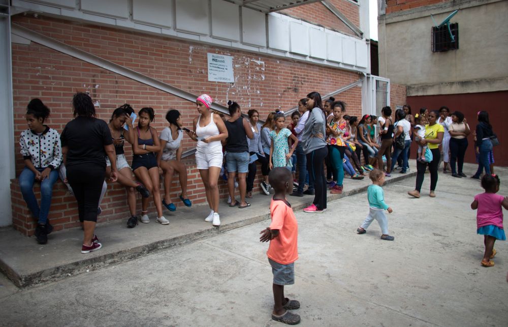In this photo taken July 25, 2019, women with their children wait outside a clinic in hopes of getting information on the next time hormonal implants to prevent pregnancies will be available, after the clinic ran out in the Caucaguita neighborhood on the outskirts of Caracas, Venezuela. The 104 implants available were not enough for the women who wanted one. (AP Photo/Ariana Cubillos) In this photo taken July 25, 2019, women with their children wait outside a clinic in hopes of getting information on the next time hormonal implants to prevent pregnancies will be available, after the clinic ran out in the Caucaguita neighborhood on the outskirts of Caracas, Venezuela. The 104 implants available were not enough for the women who wanted one. (AP Photo/Ariana Cubillos)