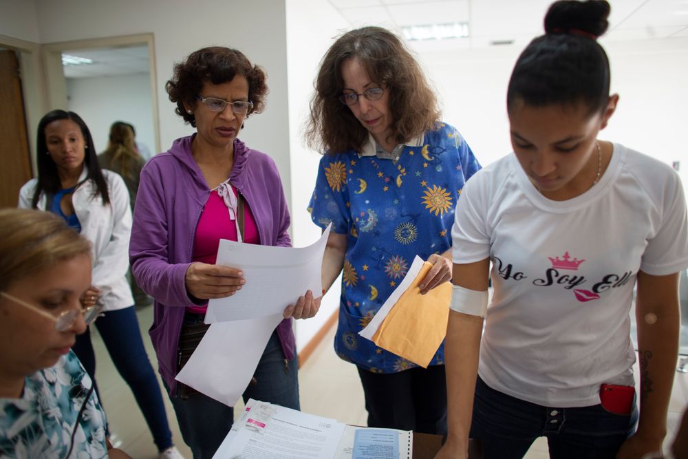 In this photo taken July 25, 2019, Dr. Saturnina Clemente, center, gives instructions to assistants at a small clinic in the Caucaguita neighborhood on the outskirts of Caracas, Venezuela. Clemente is armed with one of Venezuela's most sought-after commodities: Hormonal implants to prevent pregnancy. In this photo taken July 25, 2019, Dr. Saturnina Clemente, center, gives instructions to assistants at a small clinic in the Caucaguita neighborhood on the outskirts of Caracas, Venezuela. Clemente is armed with one of Venezuela's most sought-after commodities: Hormonal implants to prevent pregnancy.