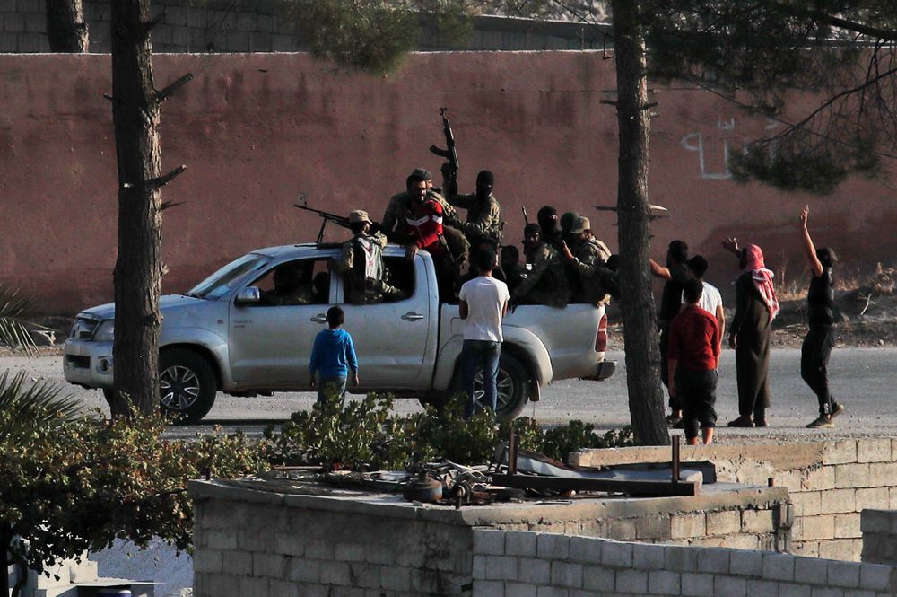 FILE - In this Sunday, Oct. 13, 2019 file photo, taken from the Turkish side of the border between Turkey and Syria, in Akcakale, Sanliurfa province, southeastern Turkey, Turkish-backed Syrian opposition fighters celebrate in Tal Abyad, Syria. The Turkish trained and funded Syrian forces present themselves as heirs to the uprising against President Bashar Assad. But while they include some Islamist and former rebel factions, a large number are Arab and Turkmen fighters from northern and eastern Syria with an ax to grind against the Kurds and a reputation for violence and looting. (AP Photo/Cavit Ozgul, File) FILE - In this Sunday, Oct. 13, 2019 file photo, taken from the Turkish side of the border between Turkey and Syria, in Akcakale, Sanliurfa province, southeastern Turkey, Turkish-backed Syrian opposition fighters celebrate in Tal Abyad, Syria. The Turkish trained and funded Syrian forces present themselves as heirs to the uprising against President Bashar Assad. But while they include some Islamist and former rebel factions, a large number are Arab and Turkmen fighters from northern and eastern Syria with an ax to grind against the Kurds and a reputation for violence and looting. (AP Photo/Cavit Ozgul, File)