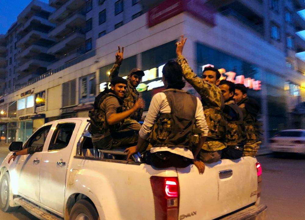 FILE - This Friday, Oct. 11, 2019 file photo, Turkish-backed Syrian opposition fighters from the Syrian National Army, flash the V-sign as they are driven through the town of Akcakale, Sanliurfa province, southeastern Turkey, on their way to enter over the border to Tel Abyad, Syria. The Turkish trained and funded Syrian forces present themselves as heirs to the uprising against President Bashar Assad. But while they include some Islamist and former rebel factions, a large number are Arab and Turkmen fighters from northern and eastern Syria with an ax to grind against the Kurds and a reputation for violence and looting. (AP Photo/Emrah Gurel, File) FILE - This Friday, Oct. 11, 2019 file photo, Turkish-backed Syrian opposition fighters from the Syrian National Army, flash the V-sign as they are driven through the town of Akcakale, Sanliurfa province, southeastern Turkey, on their way to enter over the border to Tel Abyad, Syria. The Turkish trained and funded Syrian forces present themselves as heirs to the uprising against President Bashar Assad. But while they include some Islamist and former rebel factions, a large number are Arab and Turkmen fighters from northern and eastern Syria with an ax to grind against the Kurds and a reputation for violence and looting. (AP Photo/Emrah Gurel, File)