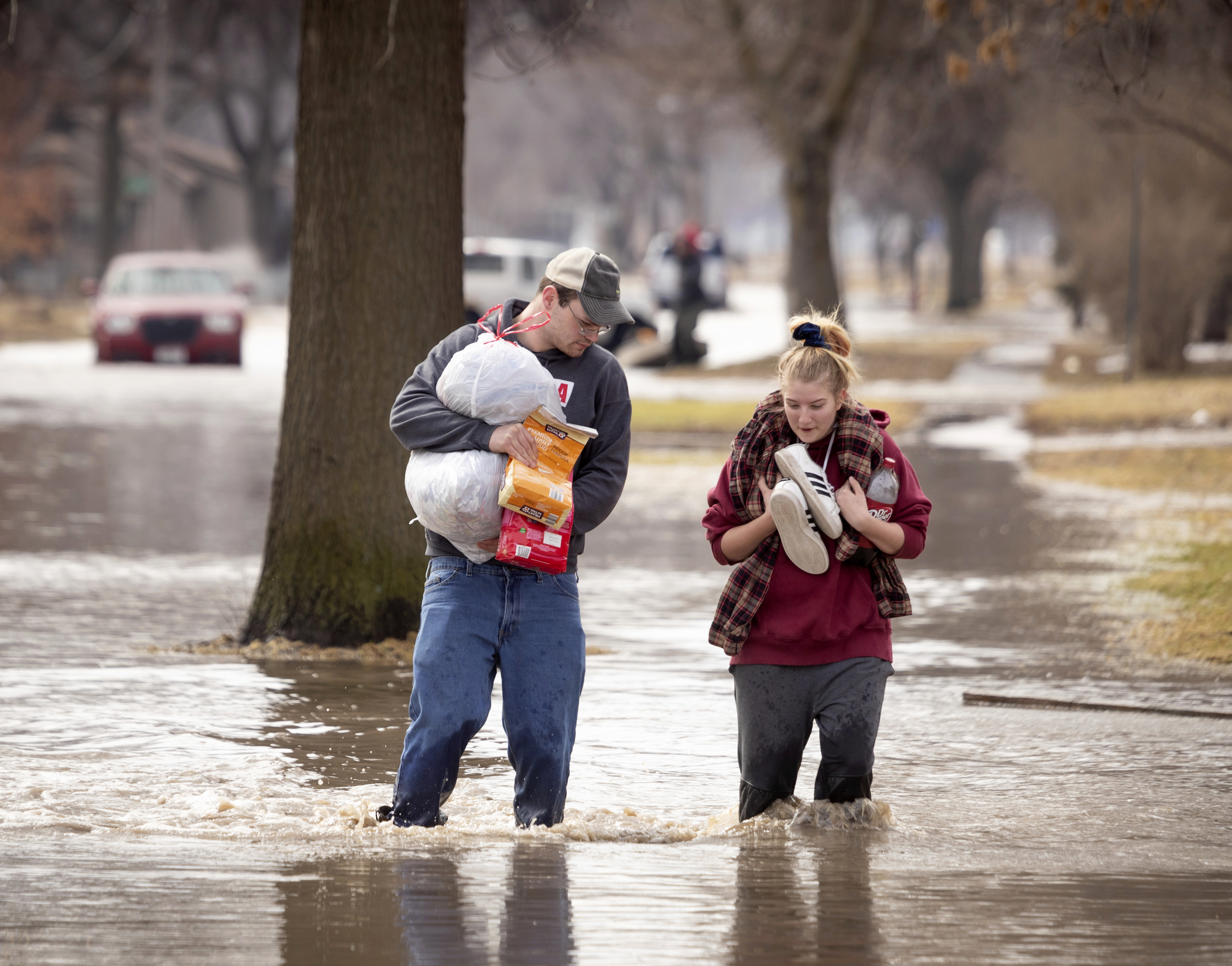 CORRECTS MONTH TO MARCH NOT MAY - Anthony Thomson, left, and Melody Walton make their way out of a flooded neighborhood Sunday, March 17, 2019, in Fremont, Neb. Hundreds of people were evacuated from their homes in Nebraska and Iowa as levees succumbed to the rush of water. (Kent Sievers/Omaha World-Herald via AP) CORRECTS MONTH TO MARCH NOT MAY - Anthony Thomson, left, and Melody Walton make their way out of a flooded neighborhood Sunday, March 17, 2019, in Fremont, Neb. Hundreds of people were evacuated from their homes in Nebraska and Iowa as levees succumbed to the rush of water. (Kent Sievers/Omaha World-Herald via AP)