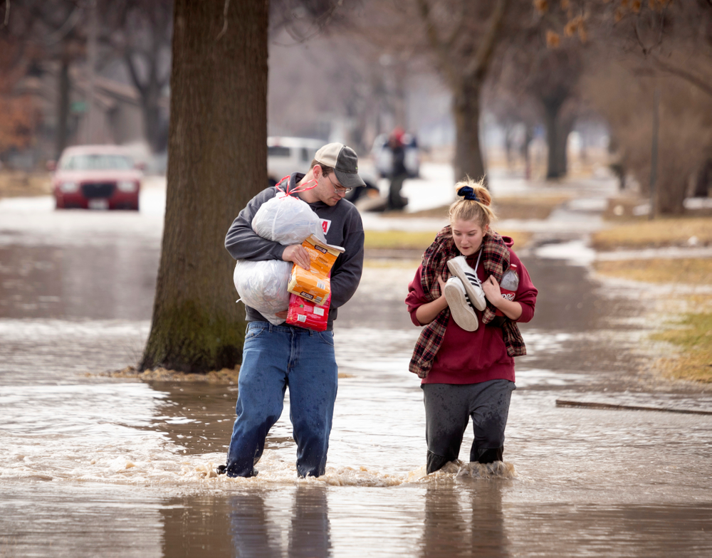 CORRECTS MONTH TO MARCH NOT MAY - Anthony Thomson, left, and Melody Walton make their way out of a flooded neighborhood Sunday, March 17, 2019, in Fremont, Neb. Hundreds of people were evacuated from their homes in Nebraska and Iowa as levees succumbed to the rush of water. (Kent Sievers/Omaha World-Herald via AP) CORRECTS MONTH TO MARCH NOT MAY - Anthony Thomson, left, and Melody Walton make their way out of a flooded neighborhood Sunday, March 17, 2019, in Fremont, Neb. Hundreds of people were evacuated from their homes in Nebraska and Iowa as levees succumbed to the rush of water. (Kent Sievers/Omaha World-Herald via AP)
