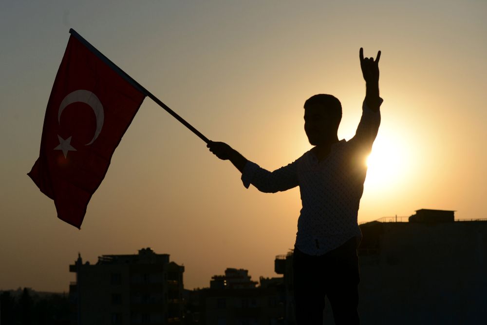A Turkish youth celebrates with a national flag after news about Syrian town of Tal Abyad, in Turkish border town of Akcakale, in Sanliurfa province, Sunday, Oct. 13, 2019. Turkey's official Anadolu news agency, meanwhile, said Turkey-backed Syrian forces have advanced into the center of a Syrian border town, Tal Abyad, on the fifth day of Turkey's military offensive. (Ismail Coskun/IHA via AP) A Turkish youth celebrates with a national flag after news about Syrian town of Tal Abyad, in Turkish border town of Akcakale, in Sanliurfa province, Sunday, Oct. 13, 2019. Turkey's official Anadolu news agency, meanwhile, said Turkey-backed Syrian forces have advanced into the center of a Syrian border town, Tal Abyad, on the fifth day of Turkey's military offensive. (Ismail Coskun/IHA via AP)
