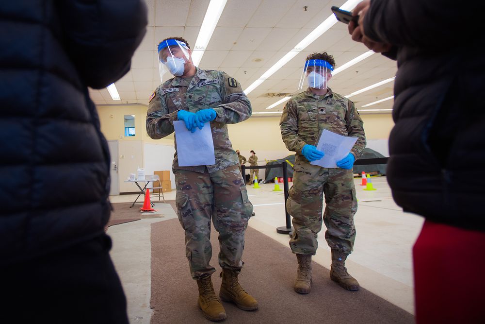 Rhode Island National Guard SPC Jose Bautista, left, SPC Alexander Genao assist patients at the former Rite Aid Building, now a state-run Covid testing site in Central Falls.
