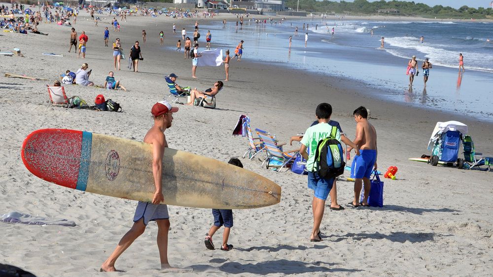 A surfer heads to the water at Narragansett Town Beach on June 25, 2020.