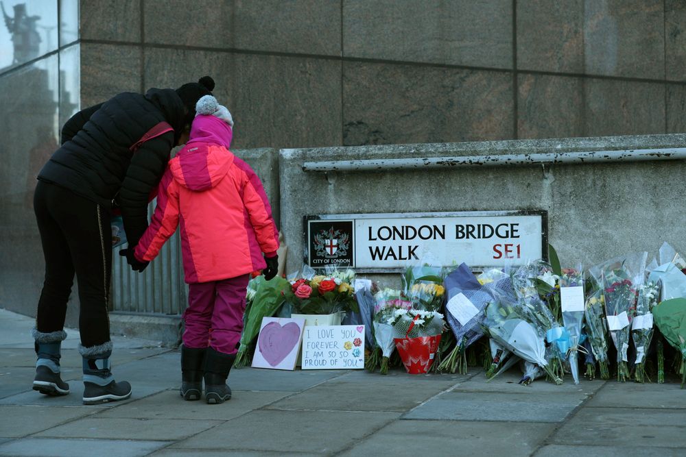 Passers-by stop to look at flowers left at London Bridge following the attack on Friday, in London, Monday, Dec. 2, 2019. London Bridge reopened to cars and pedestrians Monday, three days after a man previously convicted of terrorism offenses stabbed two people to death and injured three others before being shot dead by police. (Yui Mok/PA via AP) Passers-by stop to look at flowers left at London Bridge following the attack on Friday, in London, Monday, Dec. 2, 2019. London Bridge reopened to cars and pedestrians Monday, three days after a man previously convicted of terrorism offenses stabbed two people to death and injured three others before being shot dead by police. (Yui Mok/PA via AP)