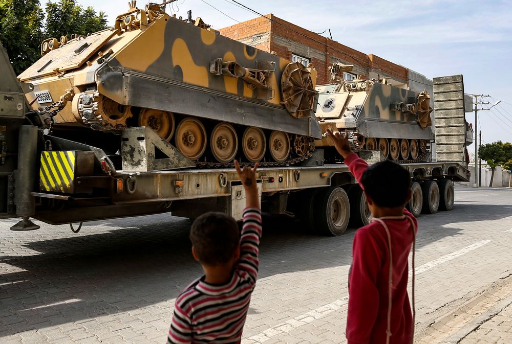 Children wave to a Turkish forces truck transporting armoured personnel carriers at the border with Syria in Karkamis, Gaziantep province, southeastern Turkey, Tuesday, Oct. 15, 2019. Turkey defied growing condemnation from its NATO allies to press ahead with its invasion of northern Syria on Tuesday, shelling suspected Kurdish positions near the border amid reports that Syrian Kurds had retaken a key town. (AP Photo/Emrah Gurel) Children wave to a Turkish forces truck transporting armoured personnel carriers at the border with Syria in Karkamis, Gaziantep province, southeastern Turkey, Tuesday, Oct. 15, 2019. Turkey defied growing condemnation from its NATO allies to press ahead with its invasion of northern Syria on Tuesday, shelling suspected Kurdish positions near the border amid reports that Syrian Kurds had retaken a key town. (AP Photo/Emrah Gurel)