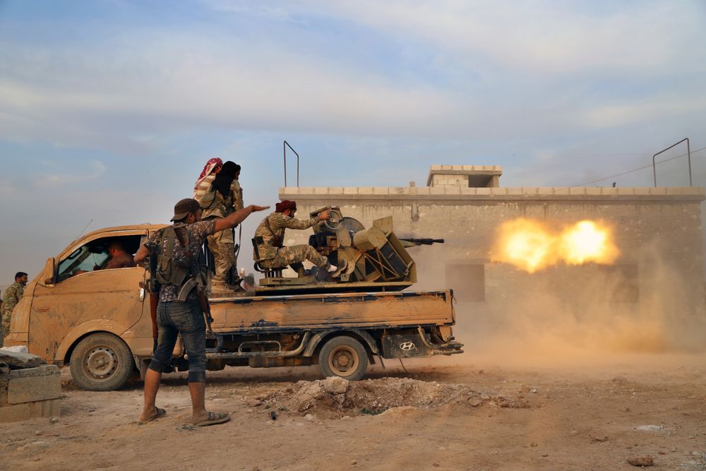 In this Monday, Oct. 14, 2019 photo, Turkey-backed Syrian opposition fighters fire a heavy machine-gun towards Kurdish fighters, in Syria's northern region of Manbij. Syrian state media said Tuesday that government forces have entered the center of the once Kurdish-held northern town of Manbij and raised the national flag. (AP Photo) In this Monday, Oct. 14, 2019 photo, Turkey-backed Syrian opposition fighters fire a heavy machine-gun towards Kurdish fighters, in Syria's northern region of Manbij. Syrian state media said Tuesday that government forces have entered the center of the once Kurdish-held northern town of Manbij and raised the national flag. (AP Photo)