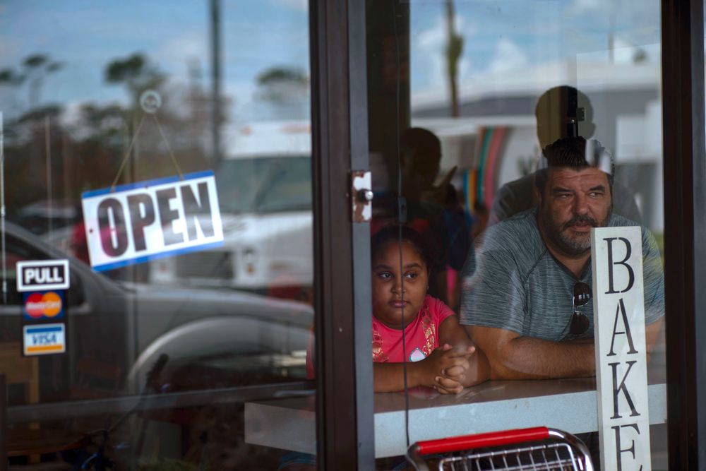 A man and girl peer out from a bakery and cafeteria in Freeport, Bahamas, Wednesday, Sept. 11, 2019. Those who survived Hurricane Dorian are facing the prospect of starting their lives over but with little idea of how or where to even begin. (AP Photo/Ramon Espinosa) A man and girl peer out from a bakery and cafeteria in Freeport, Bahamas, Wednesday, Sept. 11, 2019. Those who survived Hurricane Dorian are facing the prospect of starting their lives over but with little idea of how or where to even begin. (AP Photo/Ramon Espinosa)